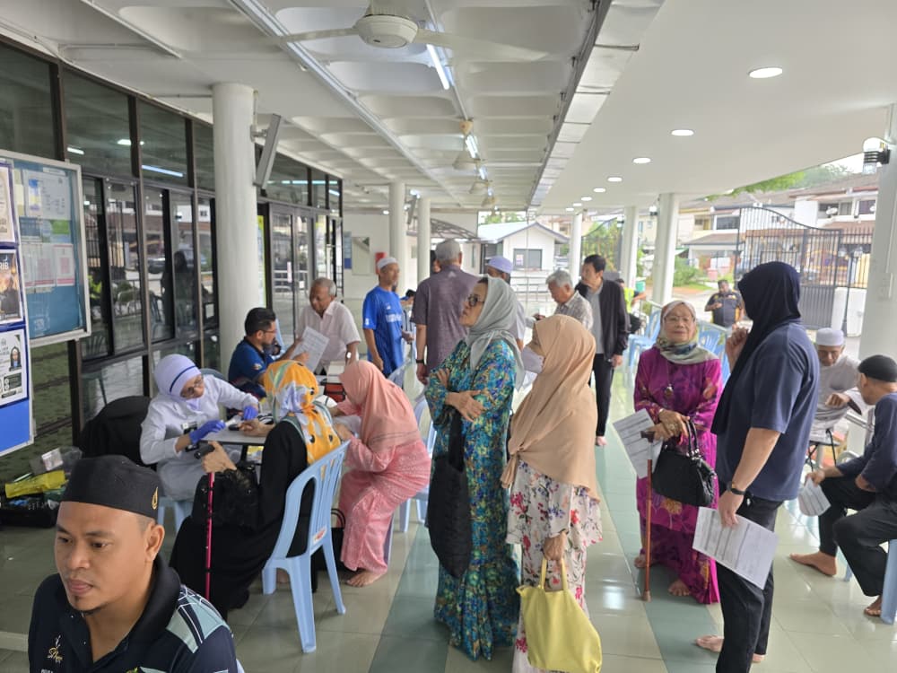 Para peserta menunggu giliran di kaunter pendaftaran dan pemeriksaan kesihatan sempena program kesihatan komuniti di masjid.